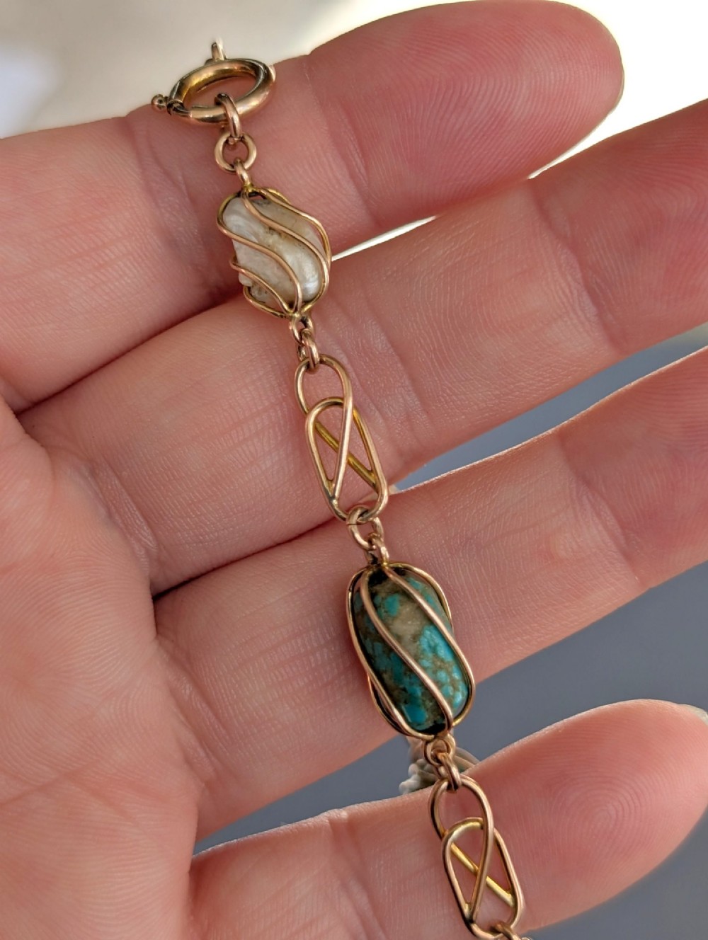 An antique 9ct rose gold bracelet featuring alternating wire-caged turquoise and pearl beads connected by openwork links with a bolt ring clasp. View IX