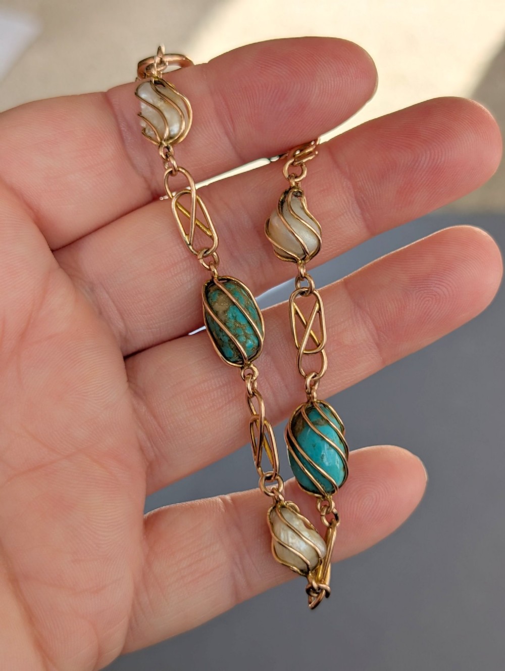 An antique 9ct rose gold bracelet featuring alternating wire-caged turquoise and pearl beads connected by openwork links with a bolt ring clasp. View X