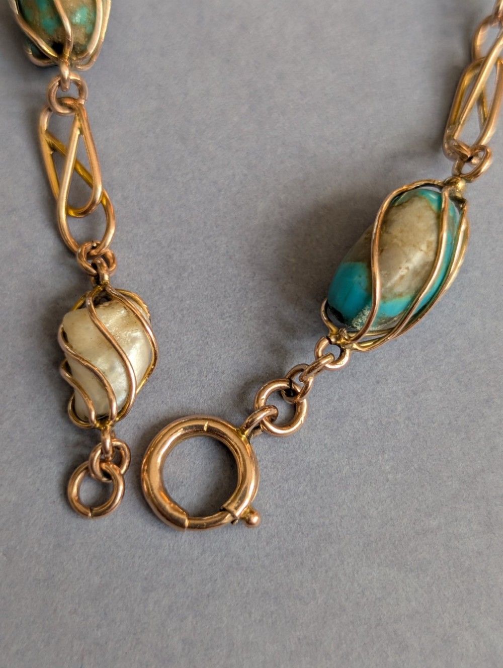 An antique 9ct rose gold bracelet featuring alternating wire-caged turquoise and pearl beads connected by openwork links with a bolt ring clasp. View XII