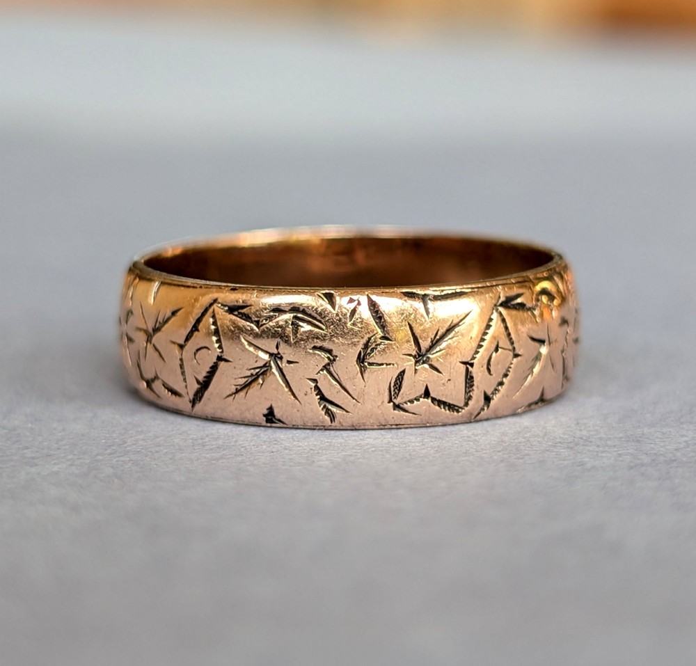 An antique 9ct rose gold wedding band featuring hand-engraved star motifs around the exterior circumference.