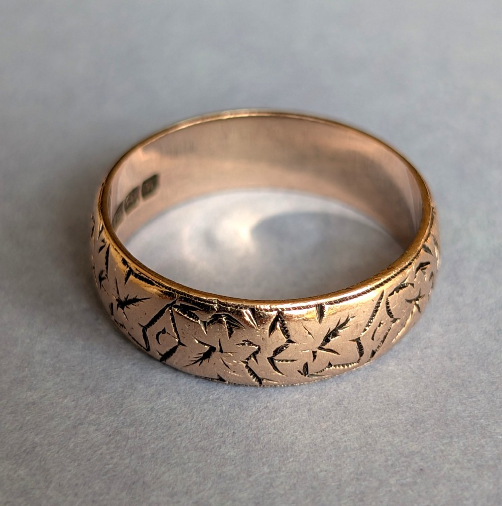 An antique 9ct rose gold wedding band featuring hand-engraved star motifs around the exterior circumference. View V