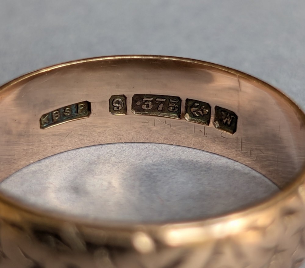 An antique 9ct rose gold wedding band featuring hand-engraved star motifs around the exterior circumference. View VI