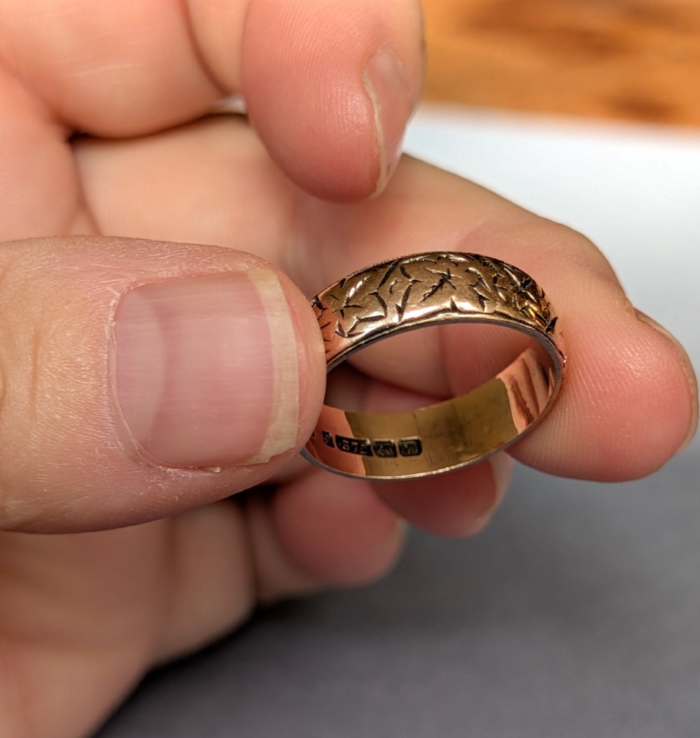 An antique 9ct rose gold wedding band featuring hand-engraved star motifs around the exterior circumference. View X