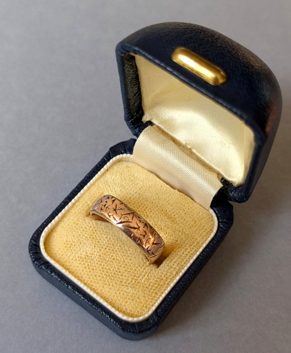 An antique 9ct rose gold wedding band featuring hand-engraved star motifs around the exterior circumference. View XII