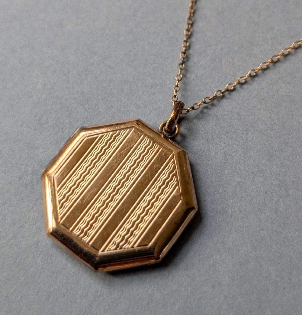 An octagonal 9ct rose gold locket featuring engine-turned geometric engraving suspended from a fine gold chain. View V