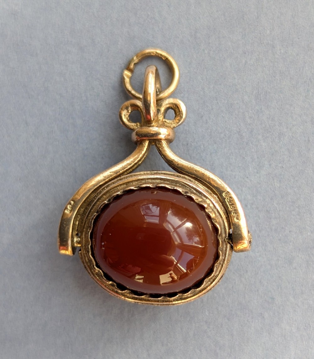 An antique 9ct yellow gold spinning fob pendant set with an oval carnelian cabochon within a swivel mount.