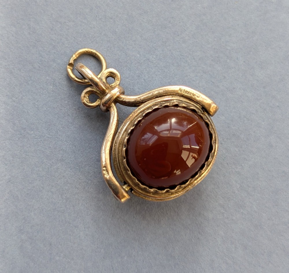 An antique 9ct yellow gold spinning fob pendant set with an oval carnelian cabochon within a swivel mount. View II