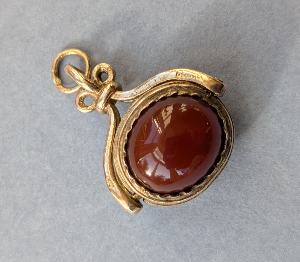 An antique 9ct yellow gold spinning fob pendant set with an oval carnelian cabochon within a swivel mount. View III
