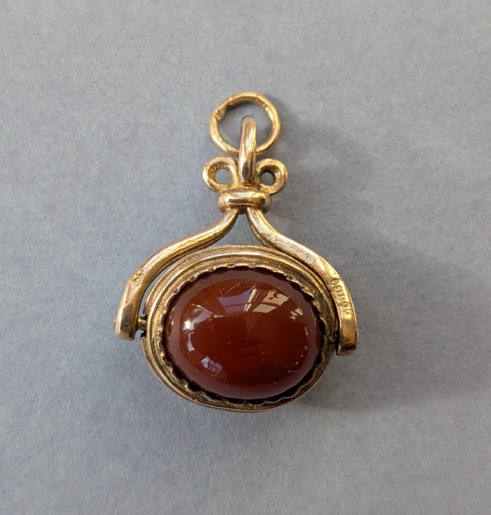 An antique 9ct yellow gold spinning fob pendant set with an oval carnelian cabochon within a swivel mount. View IV
