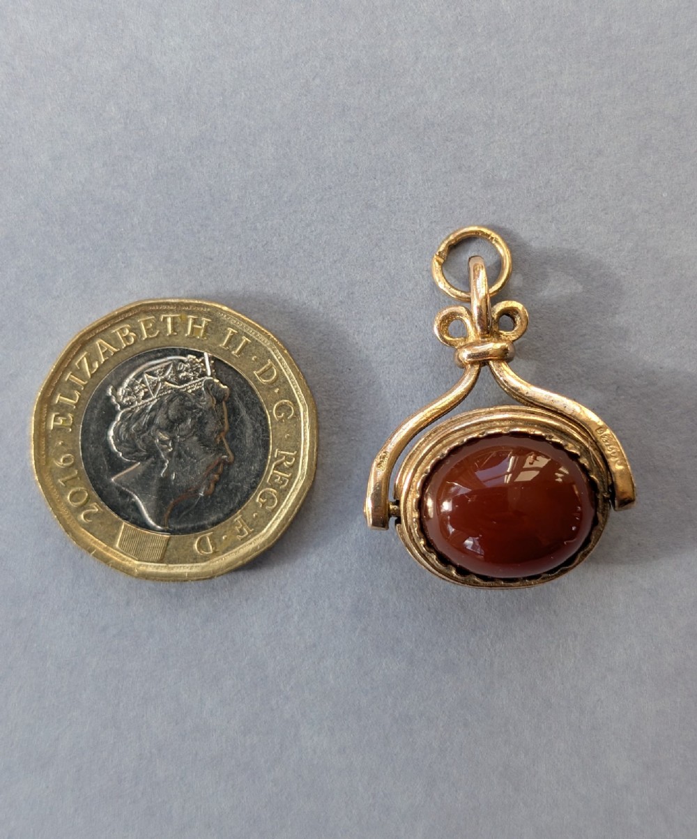 An antique 9ct yellow gold spinning fob pendant set with an oval carnelian cabochon within a swivel mount. View V