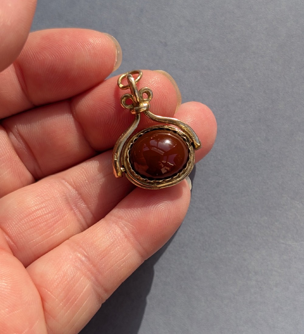 An antique 9ct yellow gold spinning fob pendant set with an oval carnelian cabochon within a swivel mount. View VI