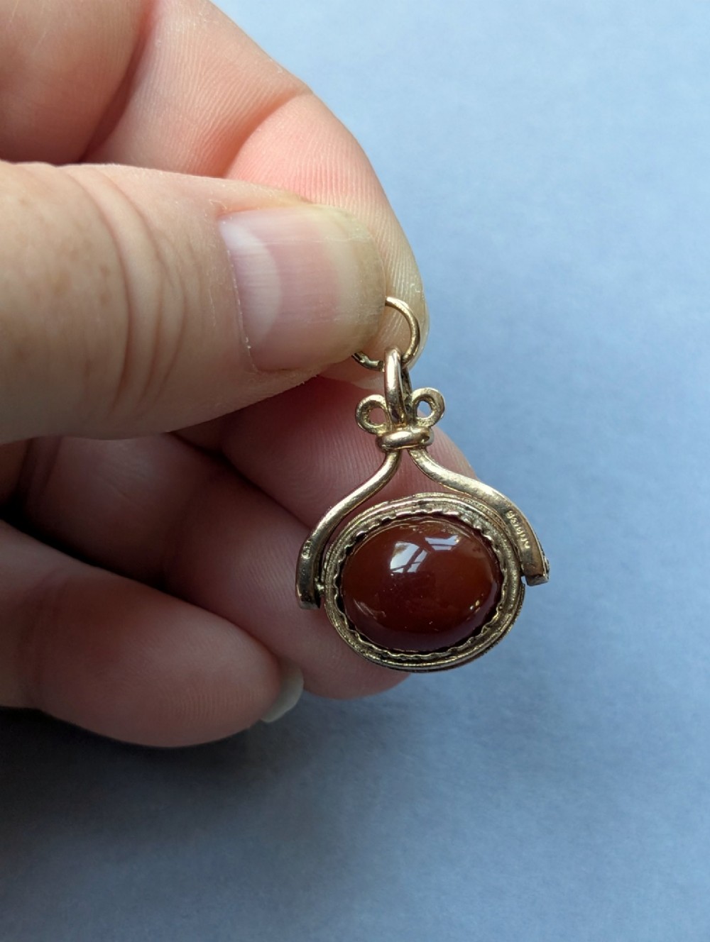 An antique 9ct yellow gold spinning fob pendant set with an oval carnelian cabochon within a swivel mount. View VII
