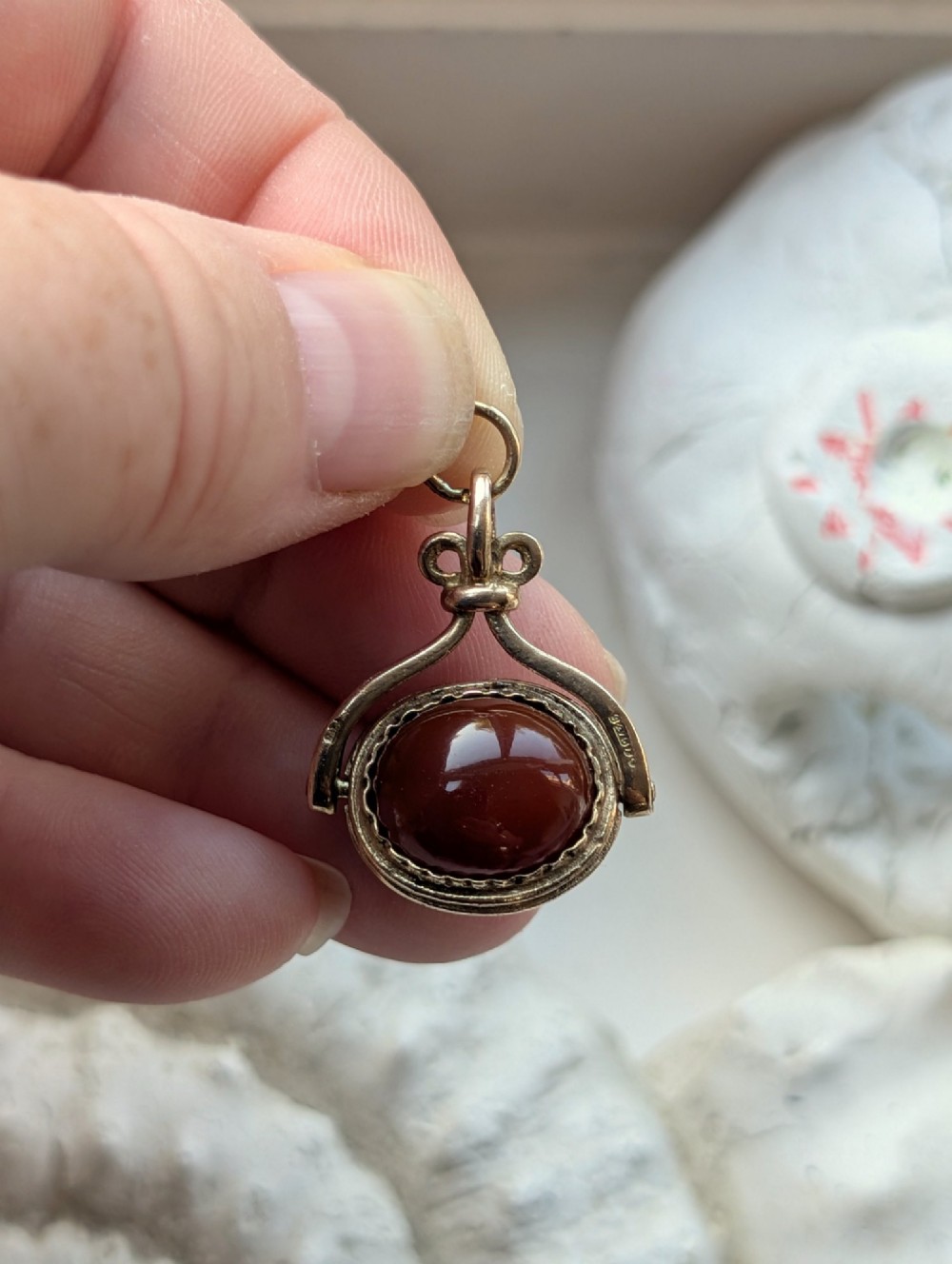 An antique 9ct yellow gold spinning fob pendant set with an oval carnelian cabochon within a swivel mount. View VIII