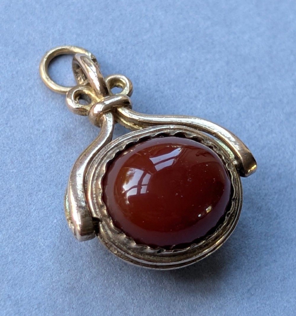 An antique 9ct yellow gold spinning fob pendant set with an oval carnelian cabochon within a swivel mount. View IX