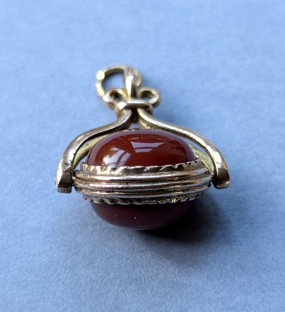 An antique 9ct yellow gold spinning fob pendant set with an oval carnelian cabochon within a swivel mount. View XI