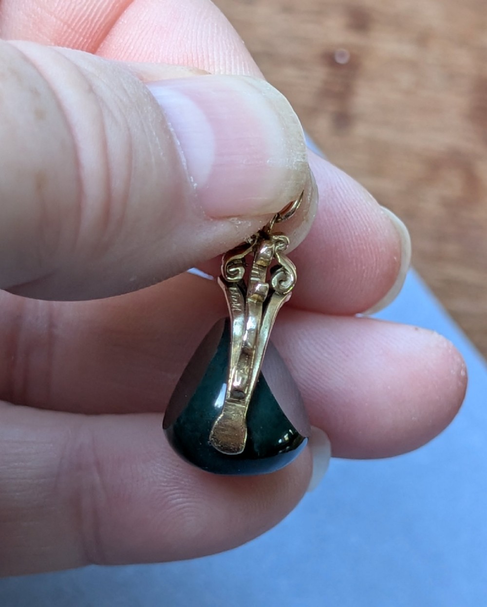 An antique 9ct gold spinning fob pendant featuring a polished dark green bloodstone within an ornate scrolled gold swivel frame. View X