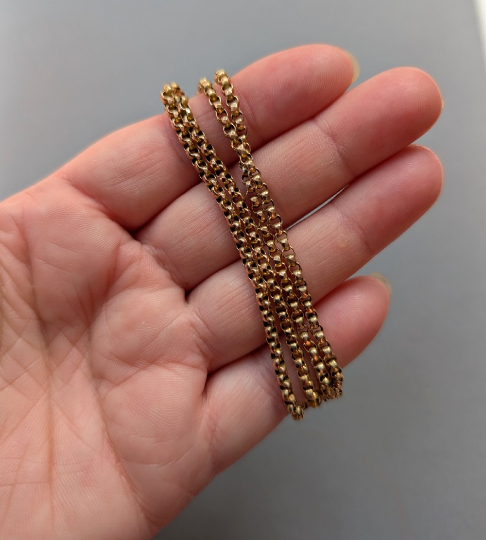 An antique 9ct yellow gold belcher chain laid on a plain background showing interlocking rounded links and a barrel fastener. View VI