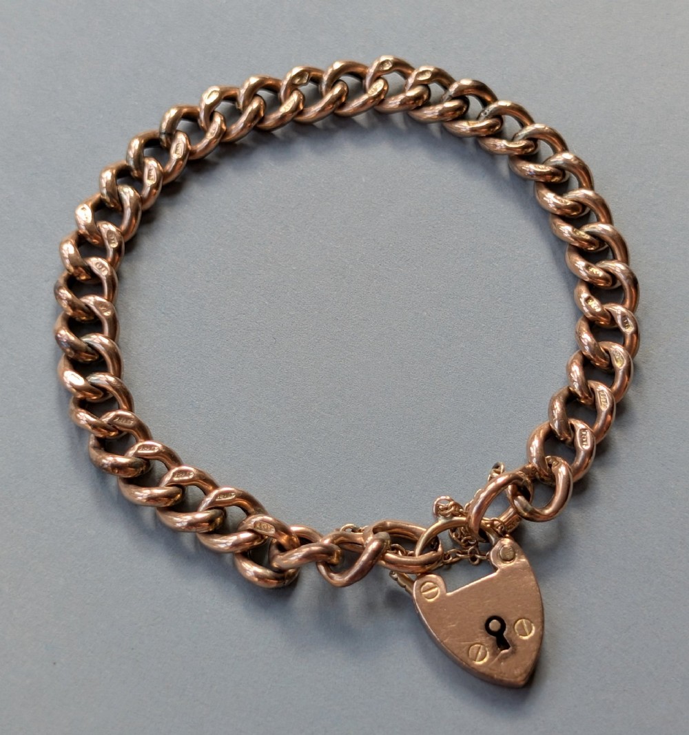 An Edwardian 9ct rose gold curb link chain bracelet featuring a heart-shaped padlock clasp and safety chain. View II
