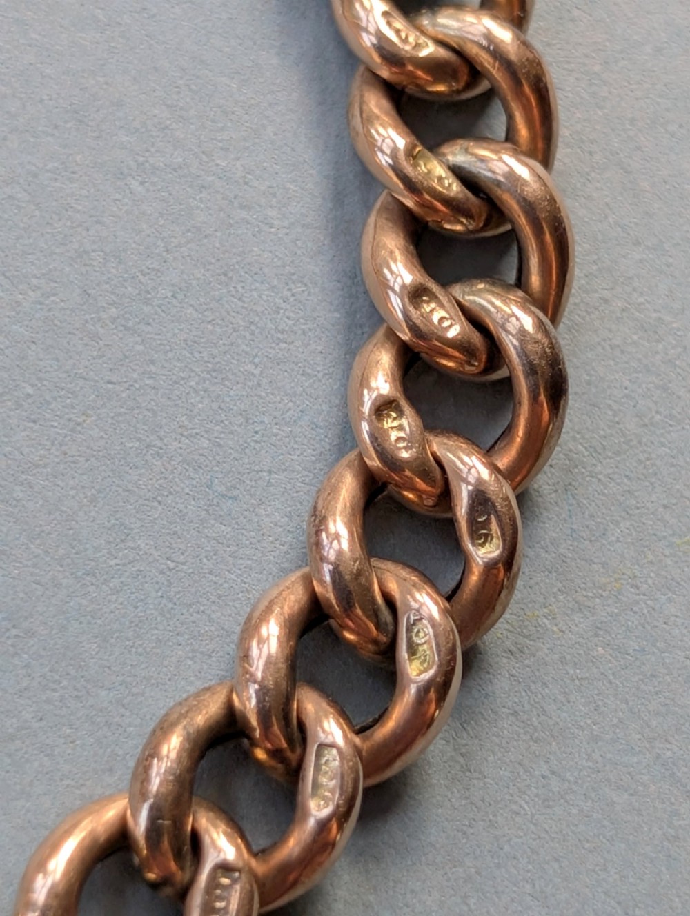 An Edwardian 9ct rose gold curb link chain bracelet featuring a heart-shaped padlock clasp and safety chain. View V