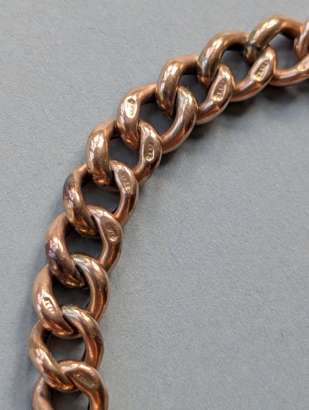 An Edwardian 9ct rose gold curb link chain bracelet featuring a heart-shaped padlock clasp and safety chain. View VI