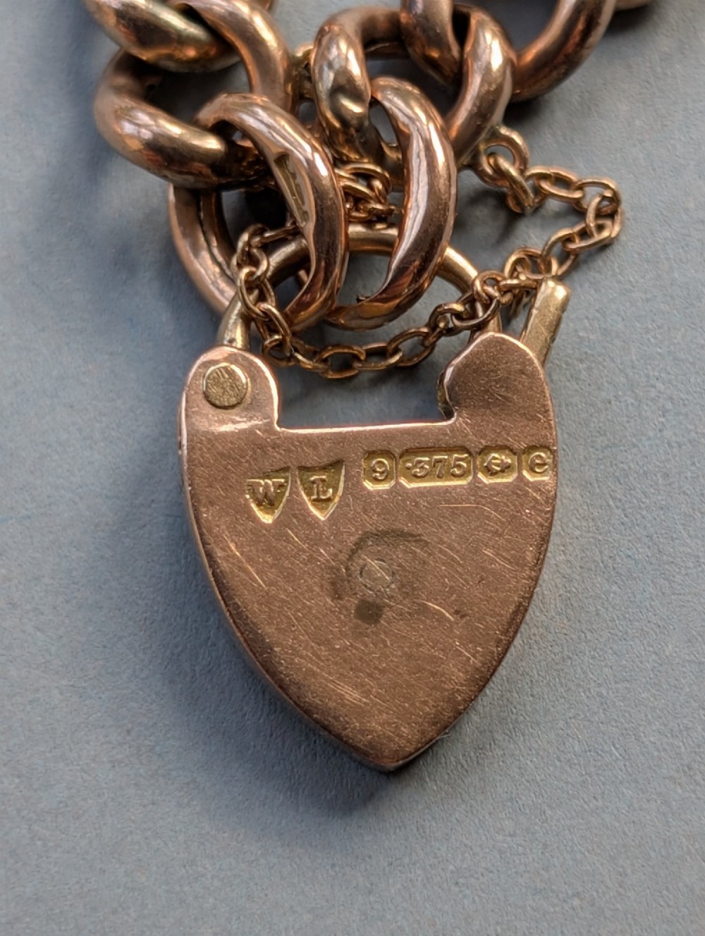 An Edwardian 9ct rose gold curb link chain bracelet featuring a heart-shaped padlock clasp and safety chain. View VII
