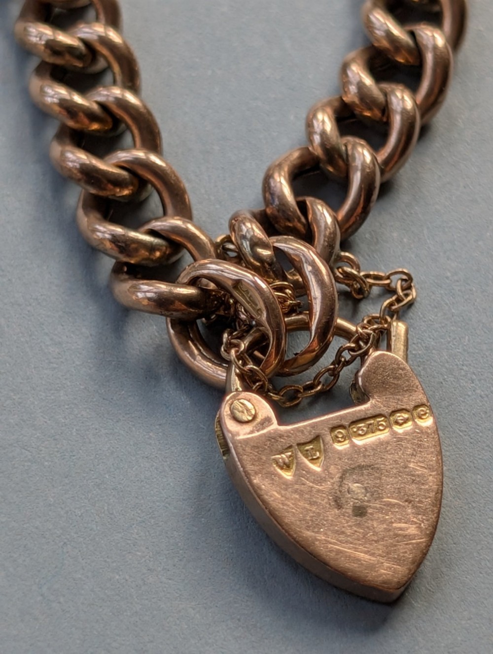 An Edwardian 9ct rose gold curb link chain bracelet featuring a heart-shaped padlock clasp and safety chain. View VIII