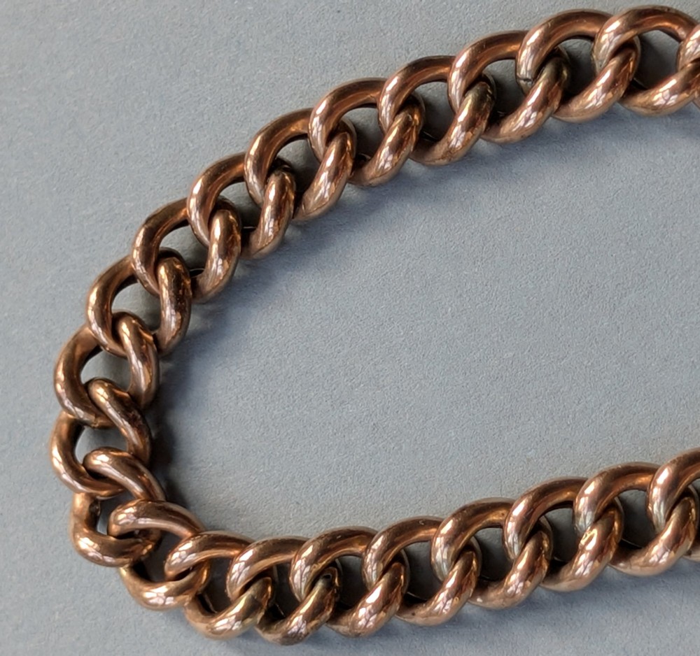 An Edwardian 9ct rose gold curb link chain bracelet featuring a heart-shaped padlock clasp and safety chain. View IX