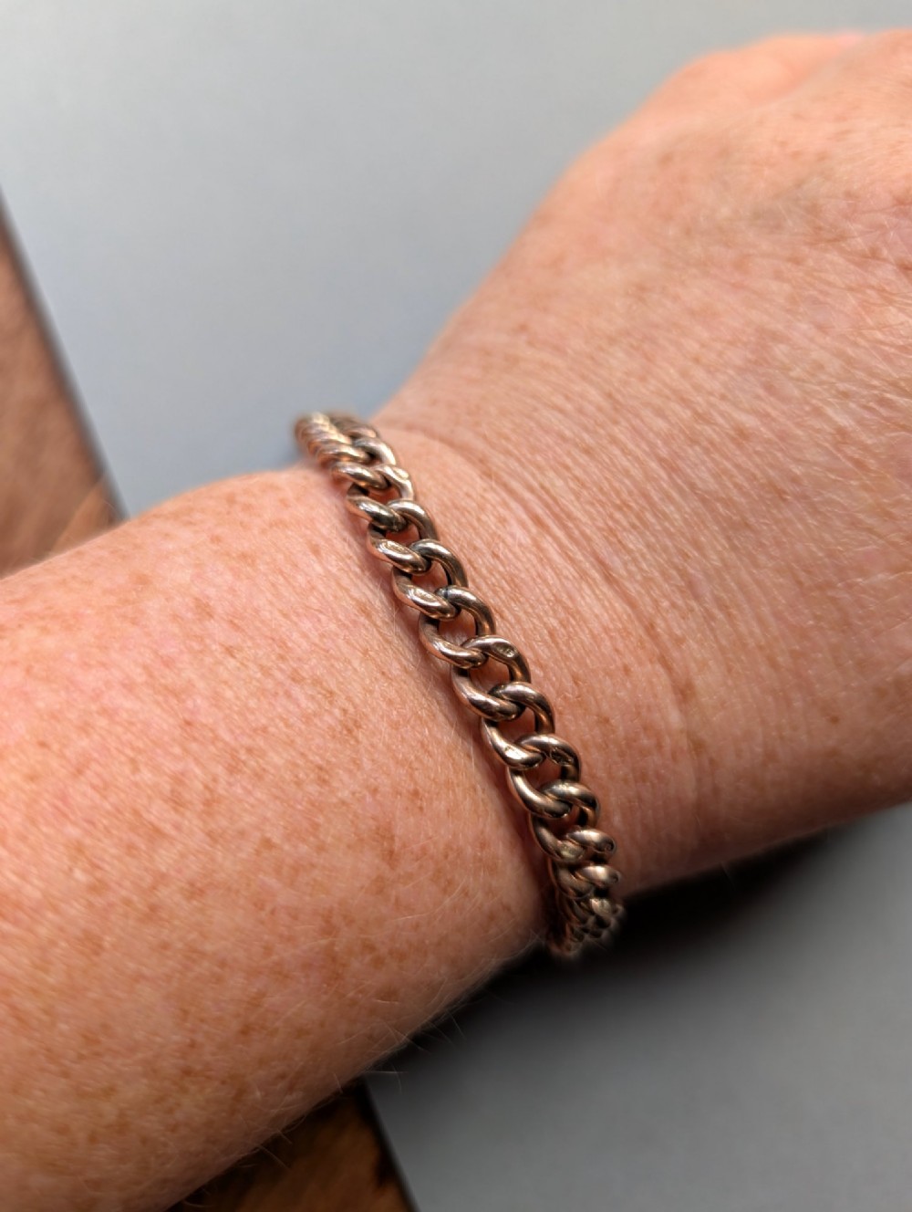 An Edwardian 9ct rose gold curb link chain bracelet featuring a heart-shaped padlock clasp and safety chain. View XI