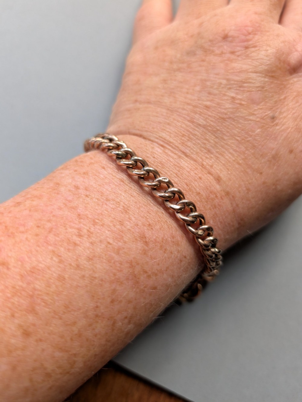 An Edwardian 9ct rose gold curb link chain bracelet featuring a heart-shaped padlock clasp and safety chain. View XII