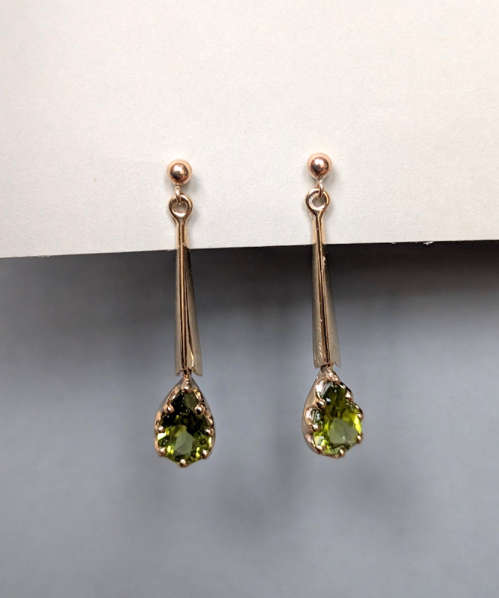 A pair of antique 9ct gold drop earrings featuring tapered bars and pear-cut green peridot gemstones suspended from ball posts. View III