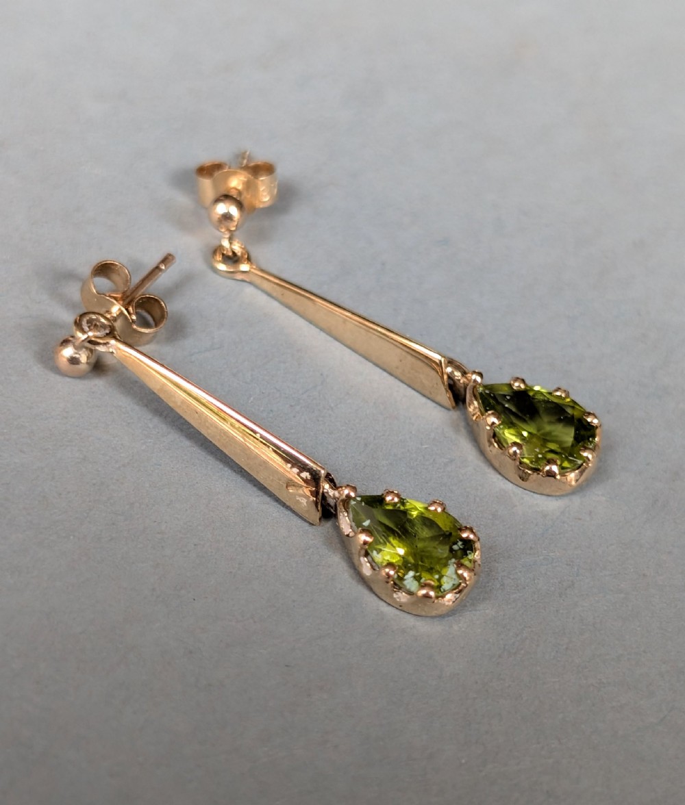 A pair of antique 9ct gold drop earrings featuring tapered bars and pear-cut green peridot gemstones suspended from ball posts. View VII