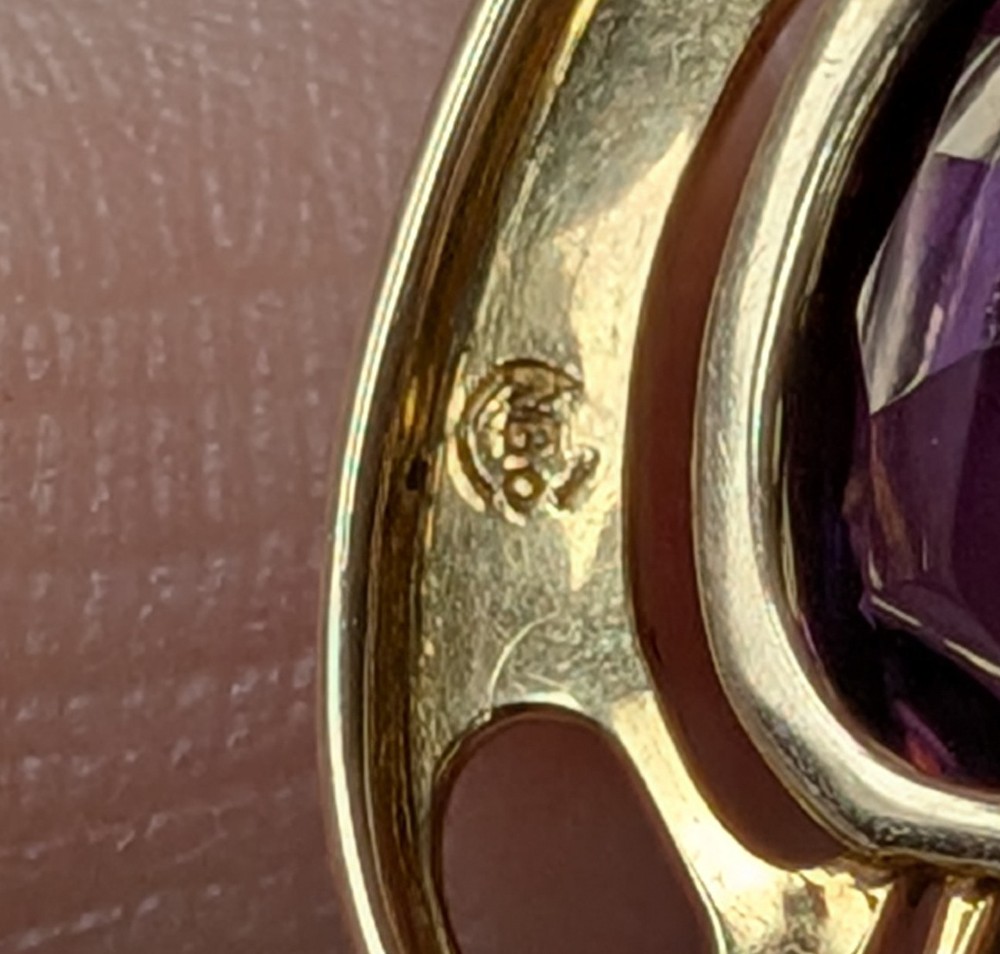 An Art Nouveau 15ct gold drop pendant featuring a central oval faceted purple amethyst framed by stylised leaf motifs with a suspended pearl at the base. View XI