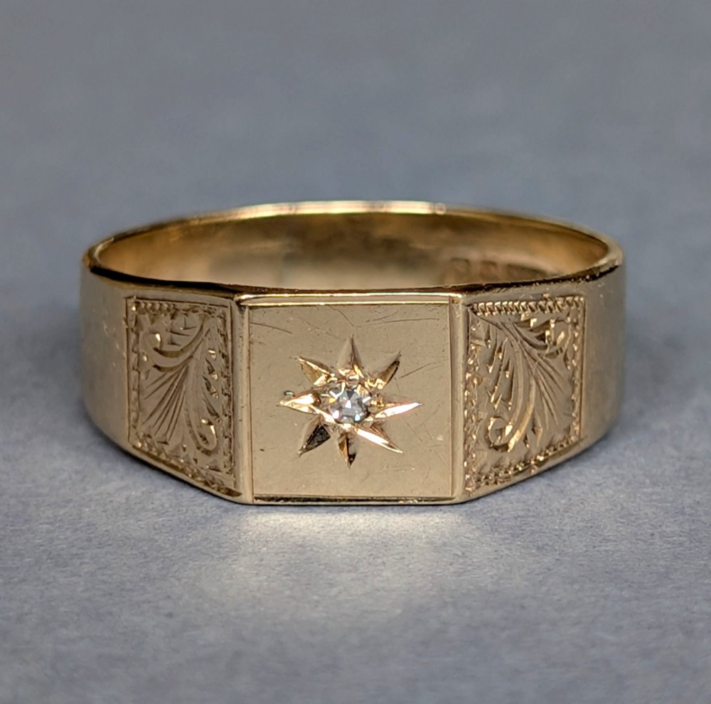A vintage 9ct yellow gold gents signet ring featuring a star-set central stone and foliate engraved shoulders. View II