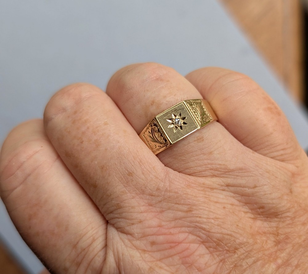 A vintage 9ct yellow gold gents signet ring featuring a star-set central stone and foliate engraved shoulders. View XII
