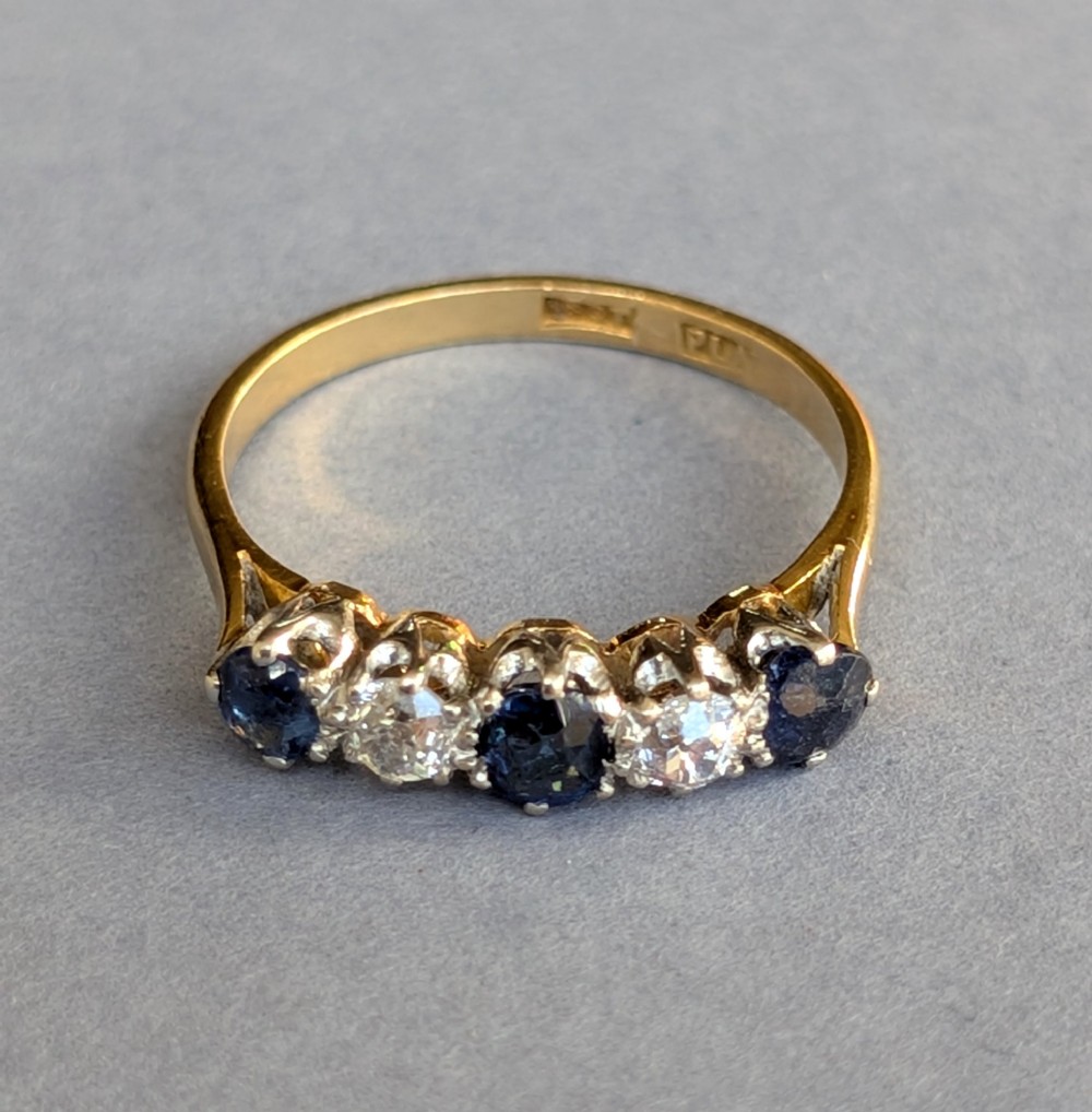 An Art Deco five-stone ring featuring three round blue sapphires alternating with two diamonds set in platinum on an 18ct yellow gold band. View VII