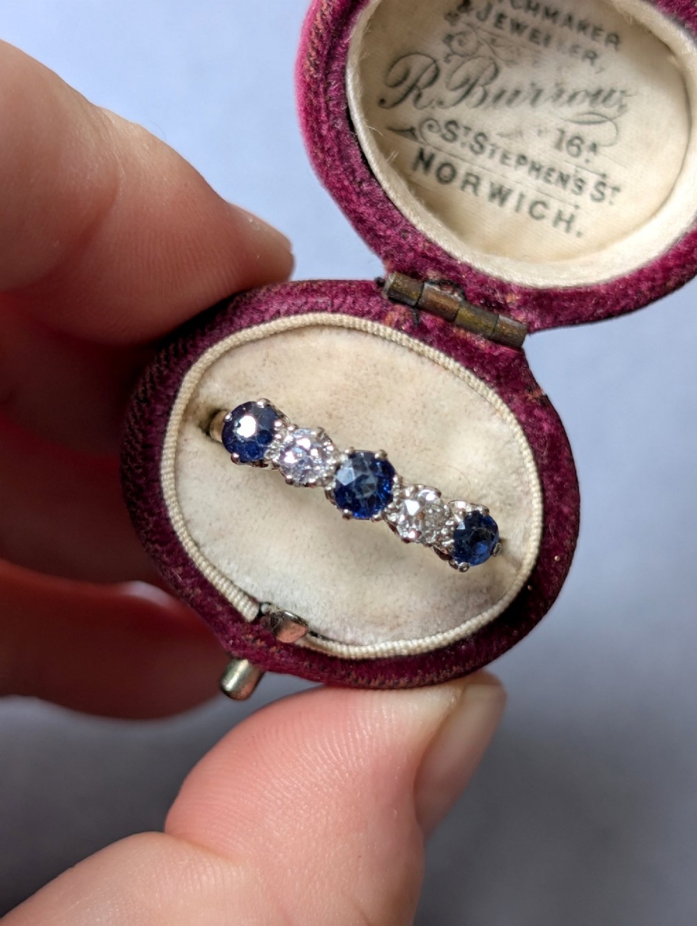 An Art Deco five-stone ring featuring three round blue sapphires alternating with two diamonds set in platinum on an 18ct yellow gold band. View XIII