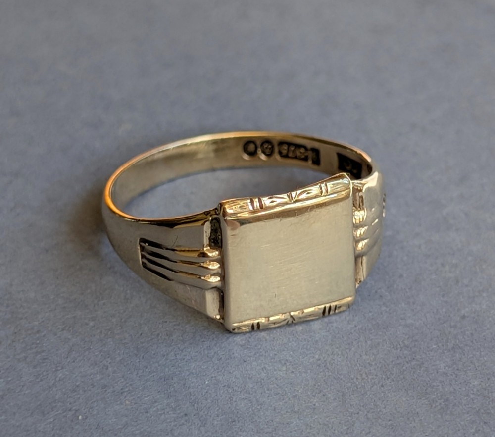A vintage 9ct yellow gold signet ring featuring a flat square face with decorative engraved top and bottom edges and grooved shoulders. View II