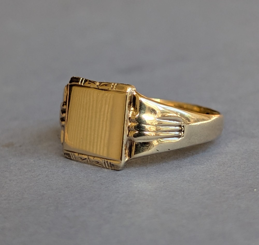 A vintage 9ct yellow gold signet ring featuring a flat square face with decorative engraved top and bottom edges and grooved shoulders. View IV