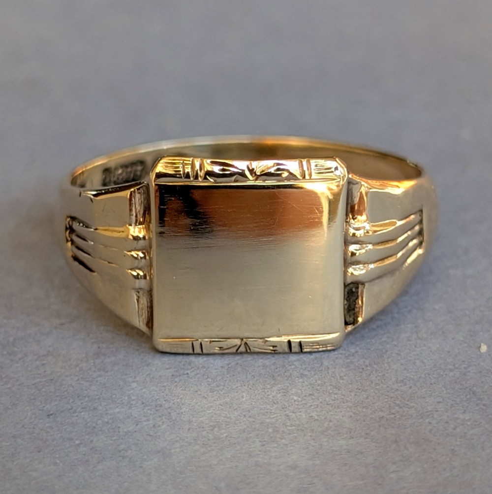 A vintage 9ct yellow gold signet ring featuring a flat square face with decorative engraved top and bottom edges and grooved shoulders.