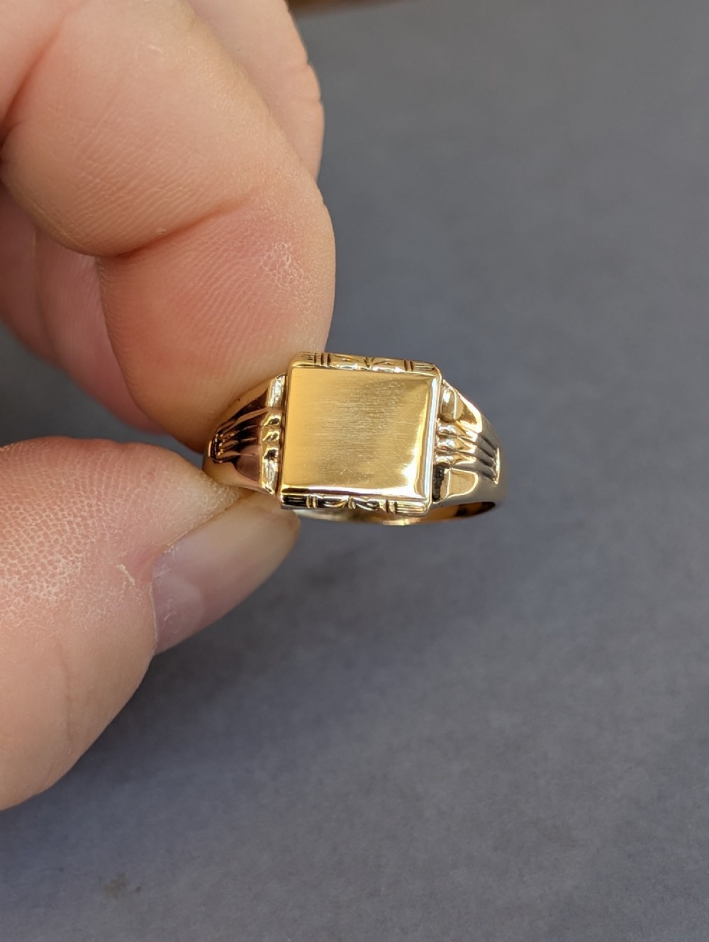A vintage 9ct yellow gold signet ring featuring a flat square face with decorative engraved top and bottom edges and grooved shoulders. View XII