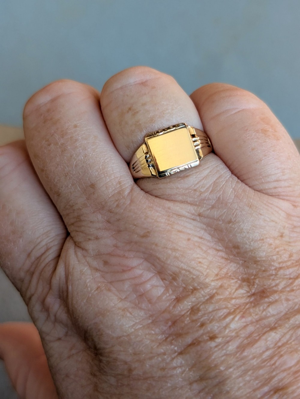 A vintage 9ct yellow gold signet ring featuring a flat square face with decorative engraved top and bottom edges and grooved shoulders. View XIV