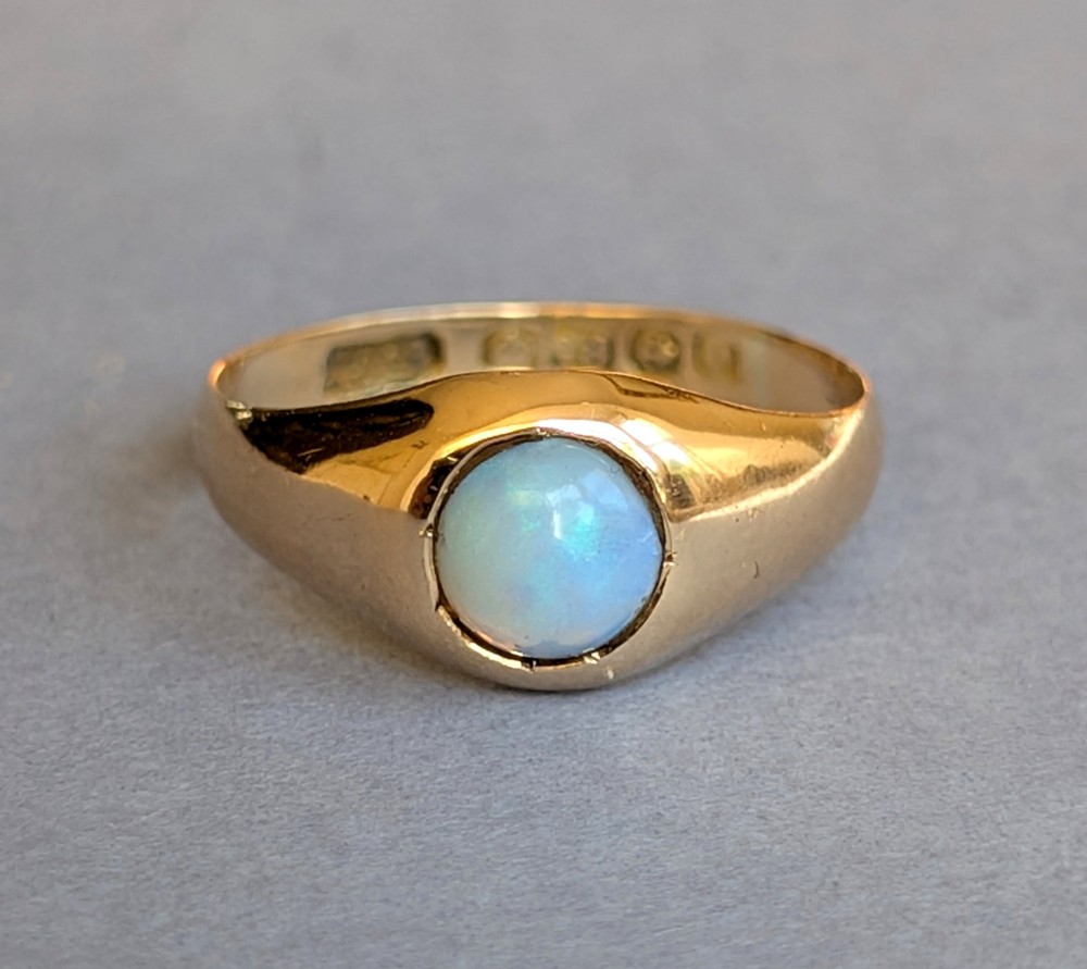 An antique yellow gold gypsy ring featuring a central round cabochon opal with blue and orange play-of-colour. View III