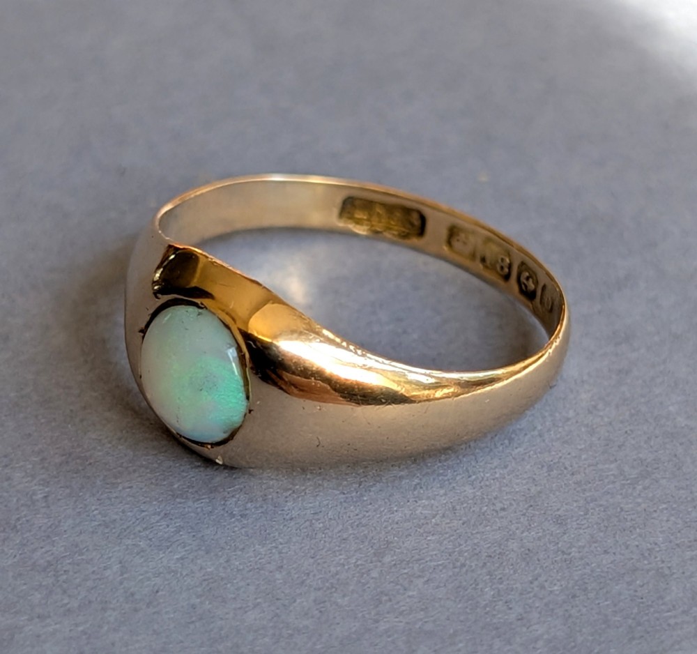 An antique yellow gold gypsy ring featuring a central round cabochon opal with blue and orange play-of-colour. View IV