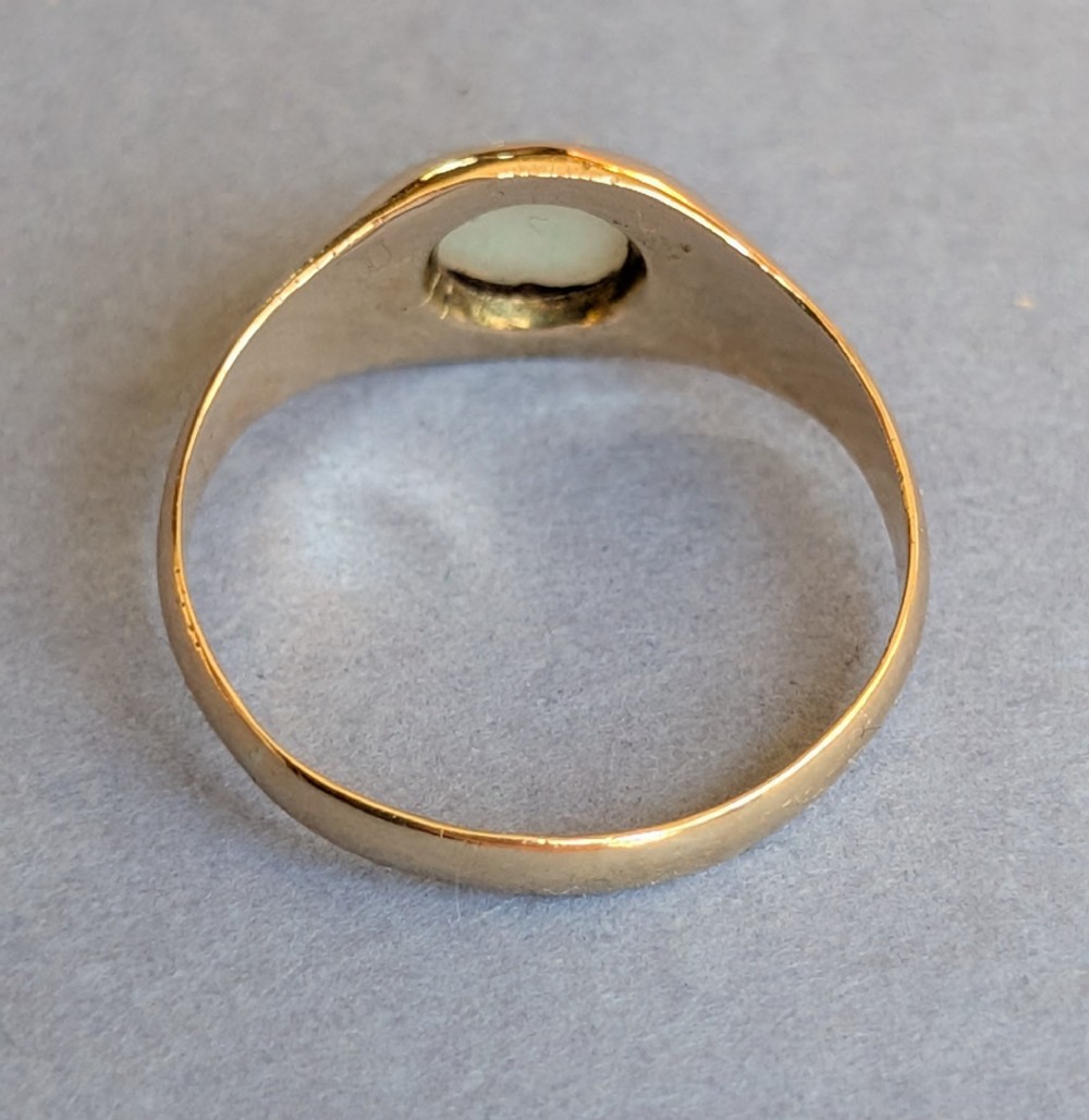 An antique yellow gold gypsy ring featuring a central round cabochon opal with blue and orange play-of-colour. View V