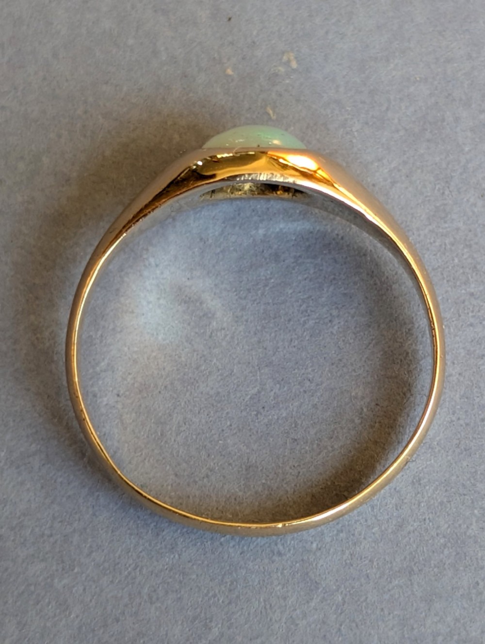 An antique yellow gold gypsy ring featuring a central round cabochon opal with blue and orange play-of-colour. View VI