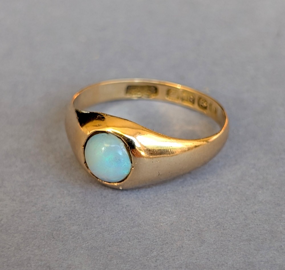 An antique yellow gold gypsy ring featuring a central round cabochon opal with blue and orange play-of-colour. View VIII