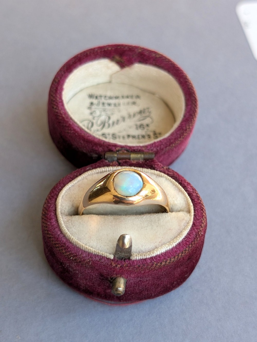An antique yellow gold gypsy ring featuring a central round cabochon opal with blue and orange play-of-colour. View XII