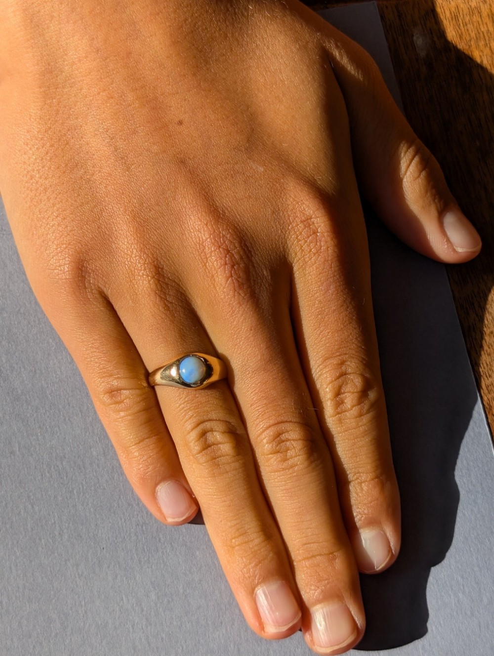 An antique yellow gold gypsy ring featuring a central round cabochon opal with blue and orange play-of-colour. View XIV