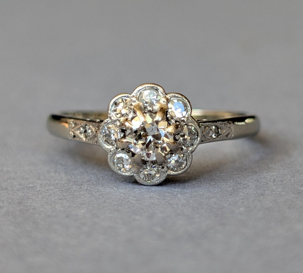 An Art Deco diamond cluster ring featuring a flower motif halo setting on a slender metallic band. View III