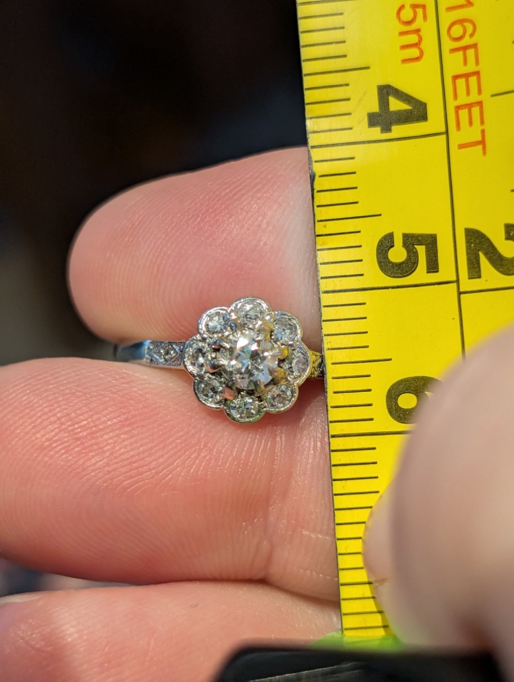 An Art Deco diamond cluster ring featuring a flower motif halo setting on a slender metallic band. View XI
